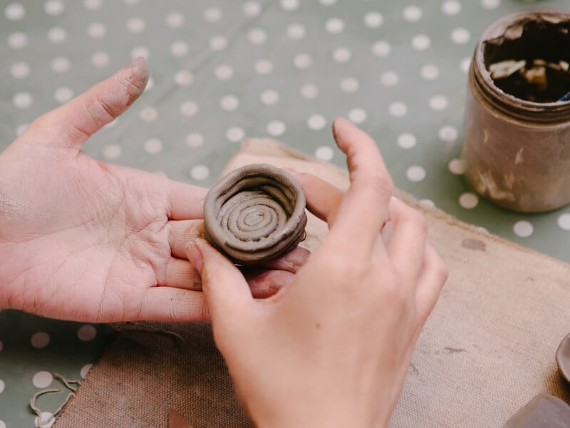 A close up of a person holding a handmade coil pot